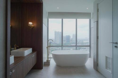 een badkamer met een groot bad en een groot raam bij Sonar Paraiso: A Dreamy Apartment in Jakarta in Madiun