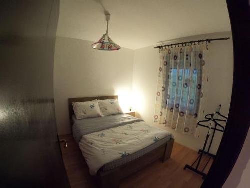 a bedroom with a bed with a light and a window at Povetarac in Divčibare