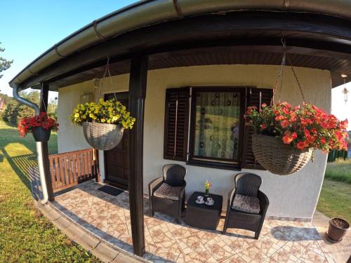 a porch with two chairs and two baskets of flowers at Povetarac in Divčibare