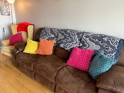 a brown couch with colorful pillows on it at Sea Breeze Cottage Mulranny in Mulranny