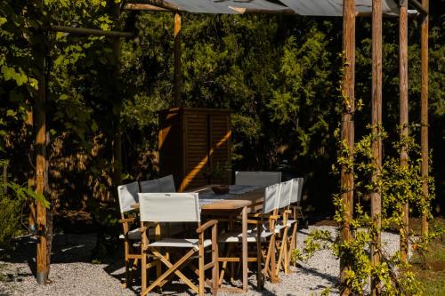 un tavolo e sedie in legno sotto un pergolato di CASENUOVE III - Casale con giardino e piscina a Castiglioncello