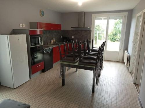 une cuisine avec une table avec des chaises et un réfrigérateur dans l'établissement Maison MANTA, à Courtils