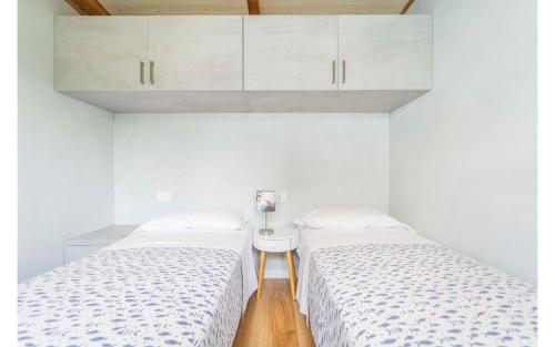 two beds in a room with white walls and wooden floors at Villaggio Smeraldo in Moneglia