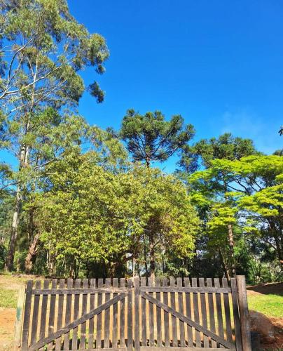 a wooden bench in a park with trees in the background at Chalé Lavanda com Hidro, Trilhas e Cachoeiras in São Francisco Xavier