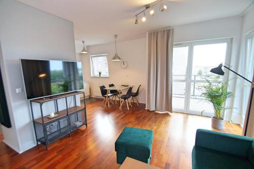 een woonkamer met een televisie en een tafel met stoelen bij Katowice, Johna Baildona, City Center in Katowice