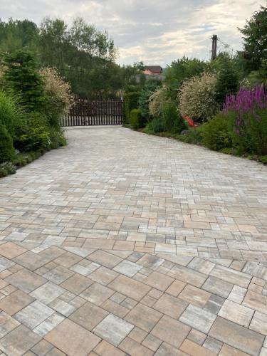 a stone driveway in a garden with a fence at Apartmán Karin in Huty