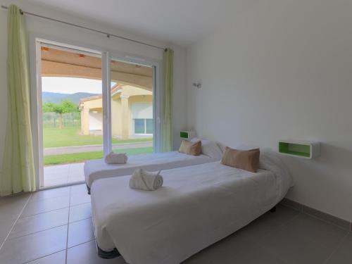 two beds in a room with a large window at Park & Suites Village Gorges de l'Hérault-Cévennes in Brissac