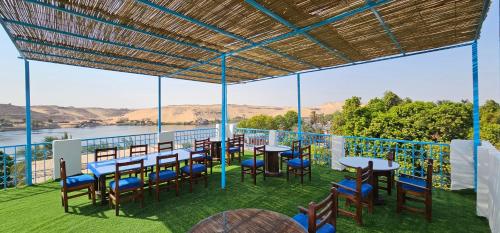 a patio with tables and chairs and a view of the water at Basmatic Nubian Guest House in Aswan