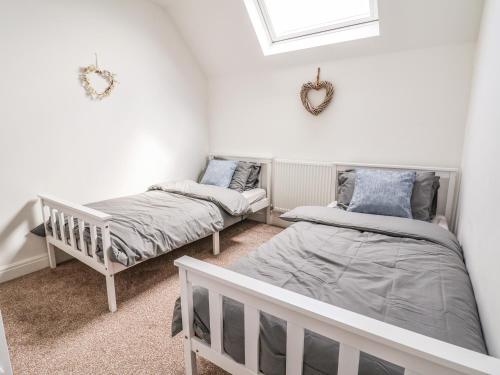 2 łóżka w pokoju z białymi ścianami w obiekcie 6 Cwrt Griffiths w mieście Rhyl
