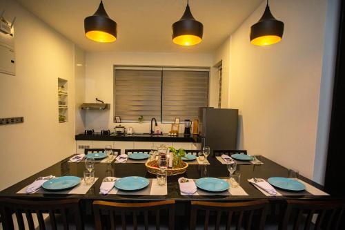 a dining room table with blue plates and wine glasses at The Pearl Residences in Galle