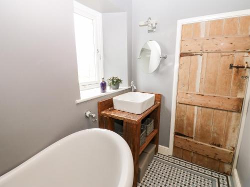 a bathroom with a sink and a wooden door at Pheasant Cottage in Richmond
