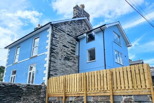 ein blaues Haus hinter einem Holzzaun in der Unterkunft Porthmadog, Sleeps 11, 5 Bedrooms, 5 Bathrooms, Mountain Views in Porthmadog