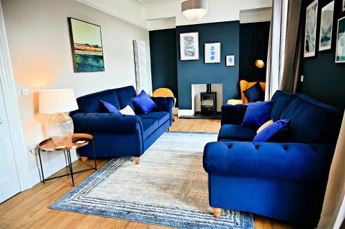 ein Wohnzimmer mit 2 blauen Sofas und einem Tisch in der Unterkunft Porthmadog, Sleeps 11, 5 Bedrooms, 5 Bathrooms, Mountain Views in Porthmadog