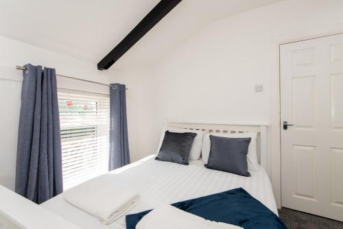een slaapkamer met een bed met blauwe kussens en een raam bij Richardson Place in Kirk Merrington