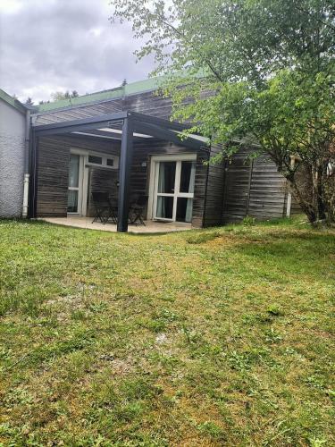 a screened in porch of a house with a yard at Au bord du lac in Royère-de-Vassivière