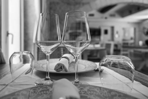 two wine glasses sitting on a table with a plate at Le Moulin de Mitou in Auriac-du-Périgord