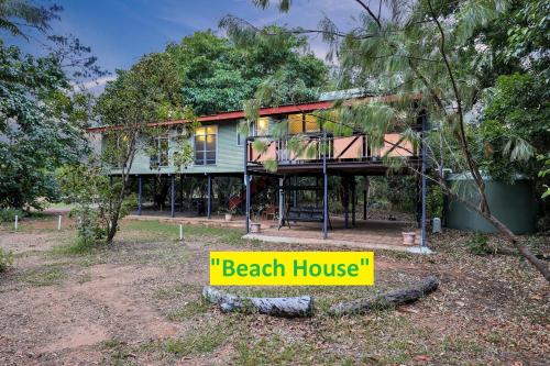 una casa en la playa con un cartel amarillo delante en Wagait Beach Holiday Houses, en Wagait Beach