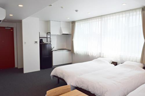 two beds in a room with a kitchen at Center Point In Kanazawa in Kanazawa