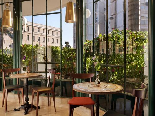 two tables and chairs in a room with windows at Prima Kings Hotel in Jerusalem