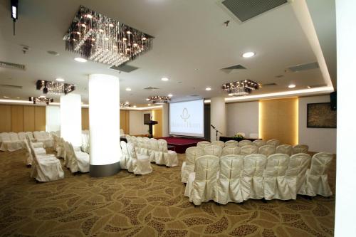 a conference room with white chairs and a screen at Badi'ah Hotel in Bandar Seri Begawan