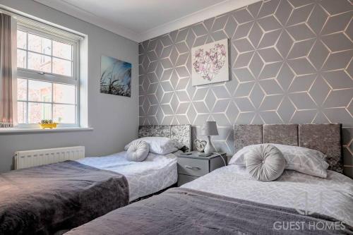 a bedroom with two beds and a wall at Guest Homes - Calthwaite House in Brough