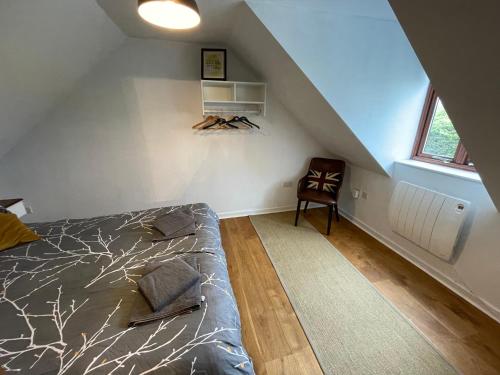 een slaapkamer op zolder met een bed en een stoel bij Meadow View @ Glebe Barn in Pershore