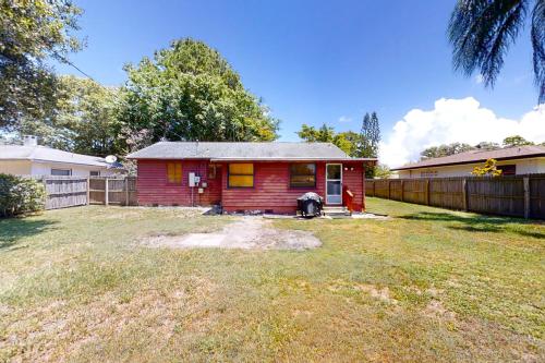 a small red house in a yard with a fence at Jupiter Pines Cottage in Clearwater