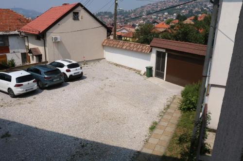 zwei Autos auf einem Parkplatz neben einem Gebäude geparkt in der Unterkunft Buba Apartment in Sarajevo