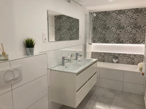La salle de bains blanche est pourvue d'un lavabo et d'une baignoire. dans l'établissement Carina Family Apartment Downtown, à Budapest