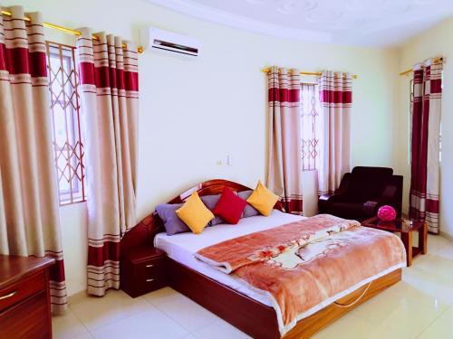 a bedroom with a bed and a chair at Renajoe Exclusive Centre in Ahwiriso
