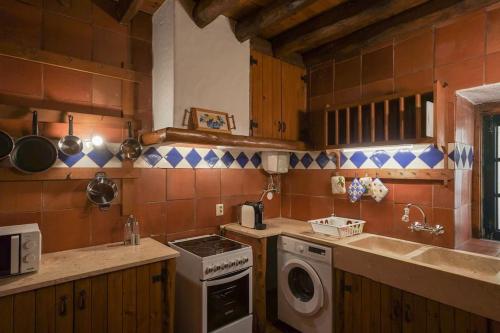 a kitchen with a stove and a washing machine at Charming Cottage in Almoçageme in Colares