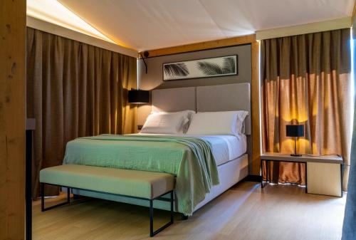 a bedroom with a bed and a bench in it at Infinito Resort in Specchiolla 