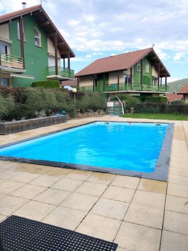 une grande piscine bleue devant une maison dans l'établissement Les chênes Rouges 4/p, à Gérardmer