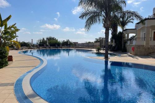 una grande piscina con una palma di fronte a un edificio di Eleona's Royal Gardens By Yiota - Luxury 2 Bed Apartment in Exclusive Complex a Peyia