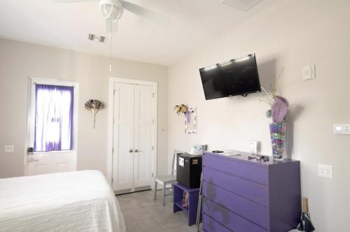 a bedroom with a purple dresser and a tv on the wall at Sunny Side Cottages in Dunedin