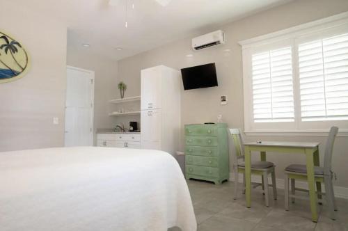 a bedroom with a white bed and a table and chairs at Sunny Side Cottages in Dunedin