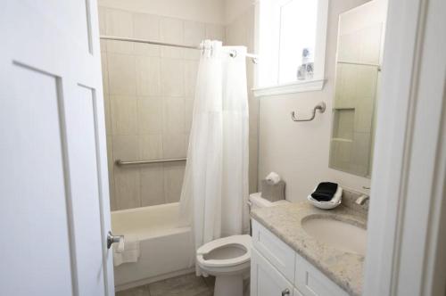 a white bathroom with a toilet and a sink at Sunny Side Cottages in Dunedin