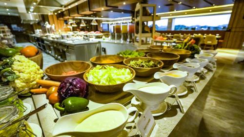 a buffet line with bowls of vegetables on a counter at FUGO Hotel Samarinda in Samarinda