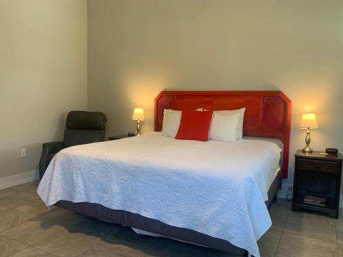a bedroom with a large bed with a red pillow at Sunny Side Cottages in Dunedin