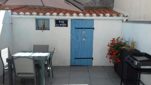 une terrasse avec une porte bleue, une table et un grill dans l'établissement Le Pélican gîte, à Les Sables-dʼOlonne