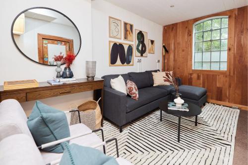 uma sala de estar com um sofá preto e um espelho em The Hampstead Wonder - Spacious 4BDR House with Balcony em Londres
