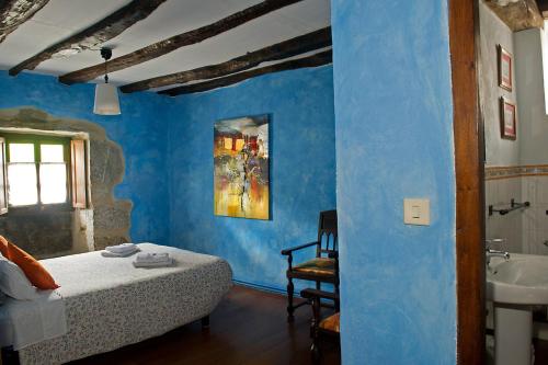 - une chambre avec des murs bleus, un lit et un lavabo dans l'établissement Etxeberri Ostatua, à Atallu