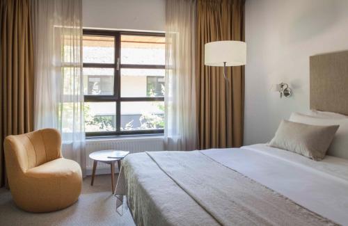 a bedroom with a bed and a chair and a window at Mooirivier in Dalfsen