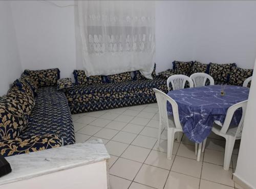 a living room with a couch and a table and chairs at Appartement zayd 4ème étage in Martil