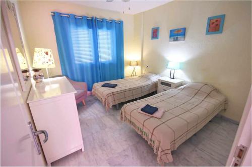 2 letti in una camera con tende blu di Dinastia D201 by Tenerife Rental and Sales a Los Cristianos