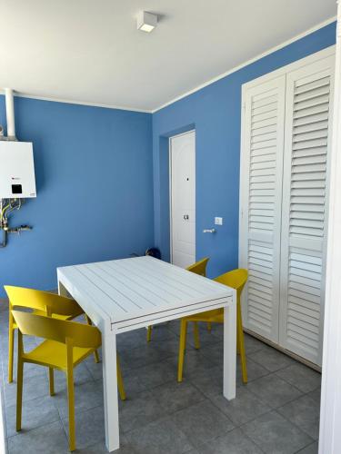 una sala da pranzo con tavolo bianco e sedie gialle di A casa di Fede a Porto Recanati