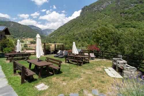 a group of picnic tables with white umbrellas and mountains at Residence Covalou in Antey-Saint-André