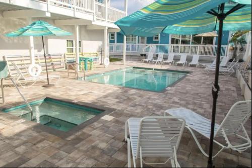 a swimming pool with chairs and umbrellas next to a building at Sunny Side Cottages in Dunedin