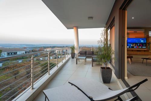 einen Balkon mit Stühlen und einen TV auf einem Gebäude in der Unterkunft CAG The Hub Bryanston in Johannesburg