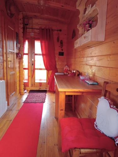 Cette chambre dispose d'une table en bois et d'un tapis rouge. dans l'établissement Roulotte la passe pierre, à Pendé